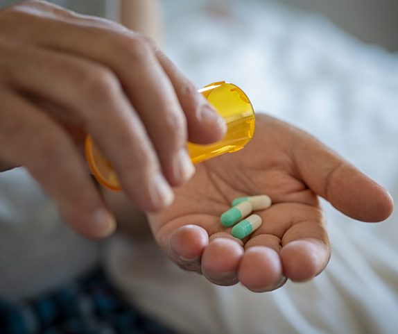 Primer plano de la mano de un hombre vertiendo cápsulas de un frasco de pastillas en la mano. Hombre mayor tomando la medicación diaria. Primer plano de las manos de un hombre tomando la dosis diaria de medicamento. 