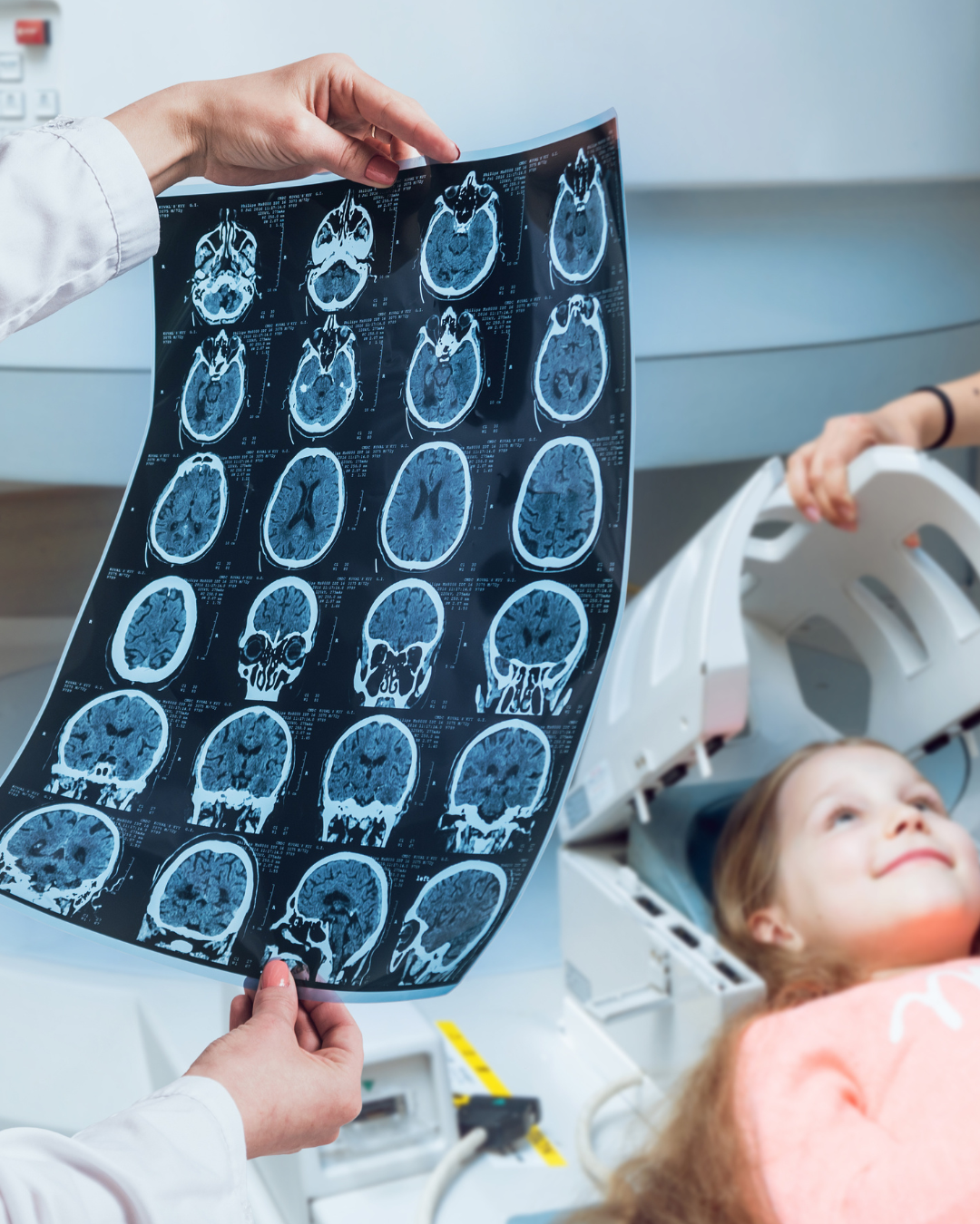 Una doctora observa una resonancia magnética mientras preparan al niño en la máquina de resonancia magnética al fondo. 